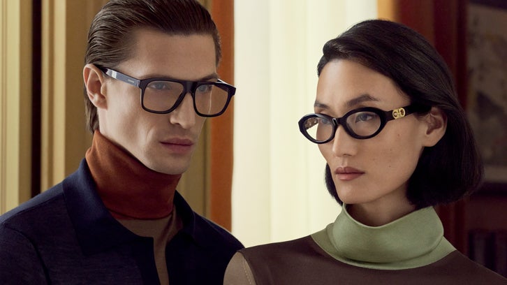 Male model wearing black Ferragamo eyeglasses and female model wearing black Ferragamo cat-eye eyeglasses